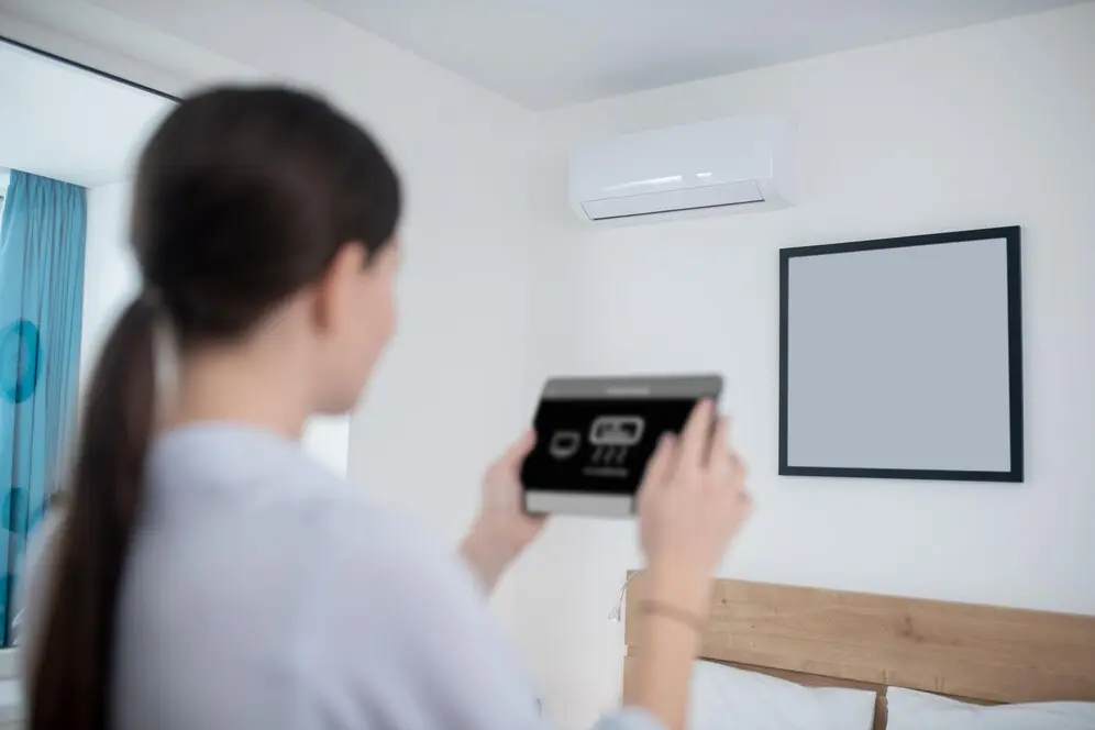 our comprehensive approach to improving your indoor air quality, woman turning air conditioner using tablet