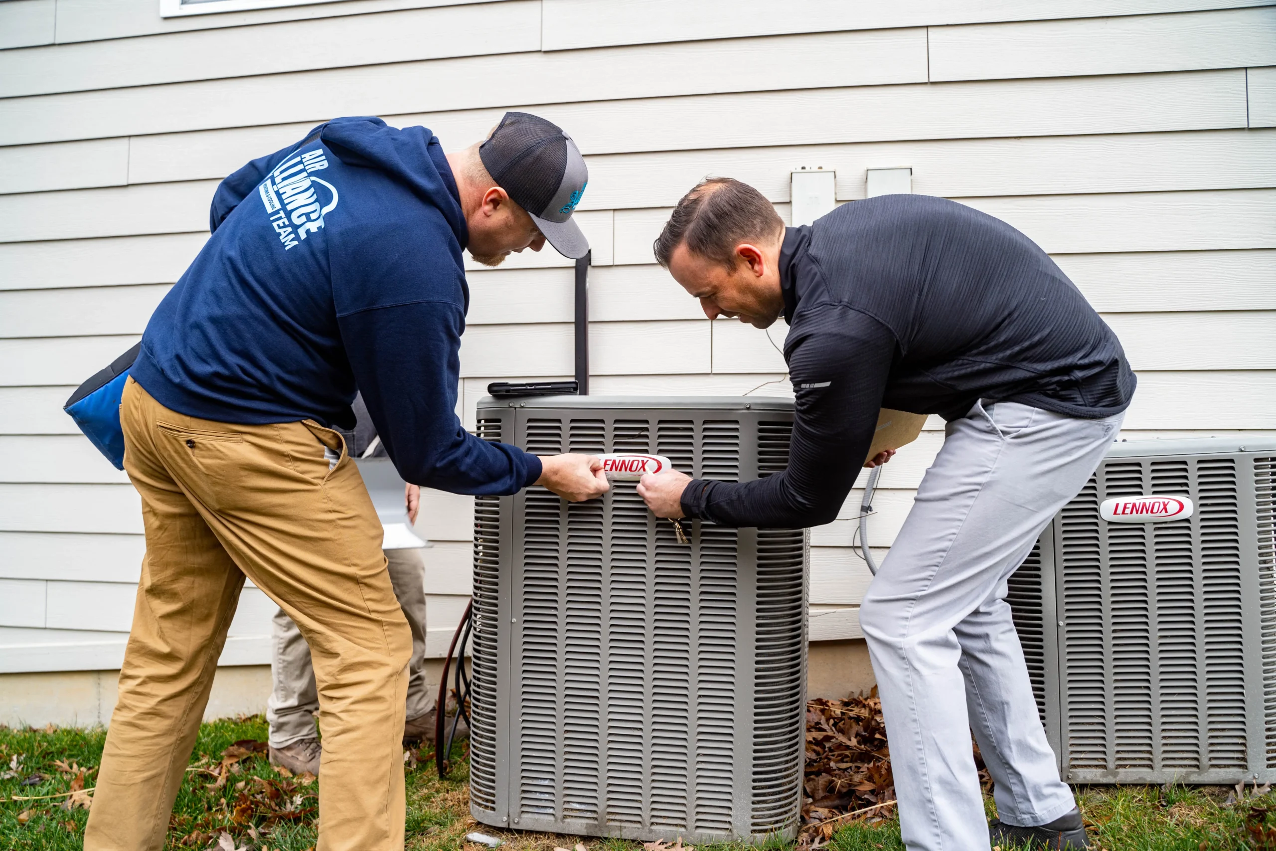 HVAC technicians performing outdoor AC unit maintenance to improve system efficiency and reduce energy waste