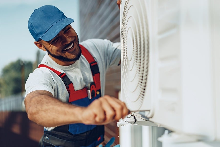 Technician performing maintenance on a commercial air conditioning unit, ensuring optimal performance and efficiency for business environments.