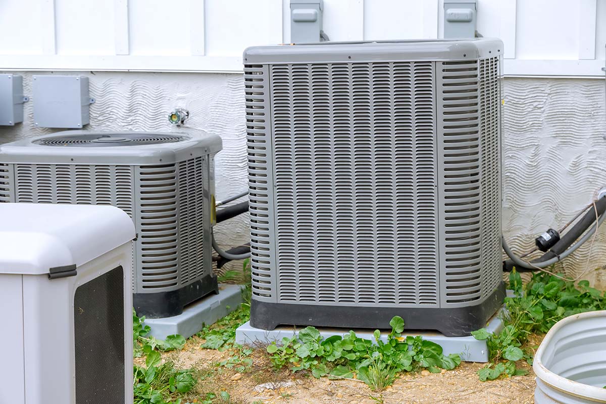 An outdoor air conditioning condenser unit installed next to a suburban home siding, featured on Air Alliance Heating & Cooling's blog discussing how to tell if your current AC is keeping your home cool enough during Missouri summers.